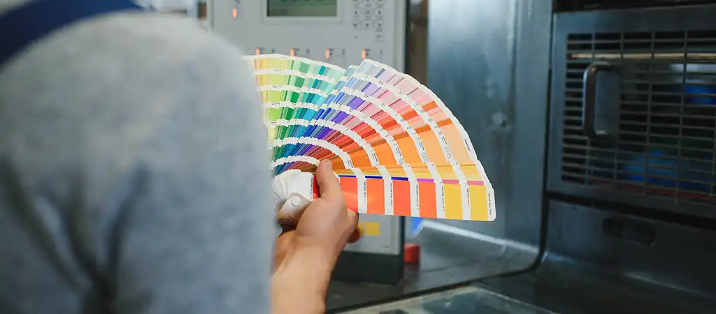 A nyomdagép beállításait ellenőrzi a gépmester egy színskála segítségével, hogy a nyomtatott anyag színhelyessége megfelelő legyen.