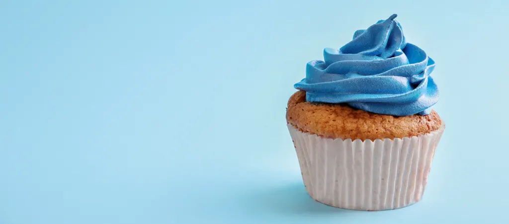 A kék szín jelentése és felhasználása a designban, muffin világoskék kreatív cukormázzal, letisztult háttéren.
